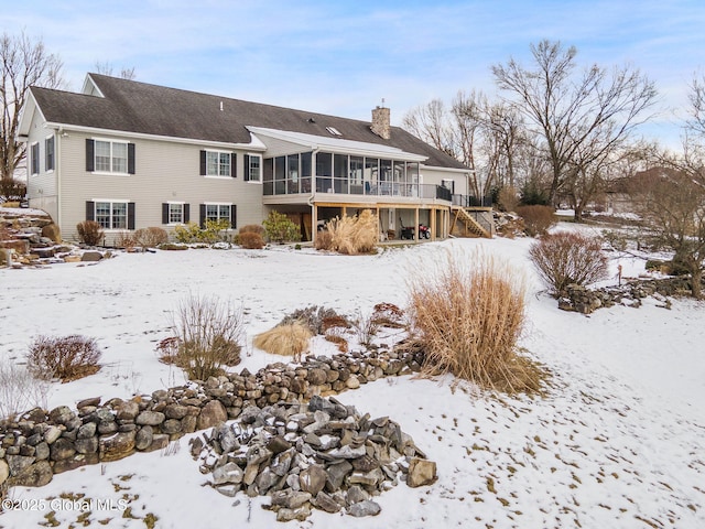 snow covered house featuring a sunroom and a deck