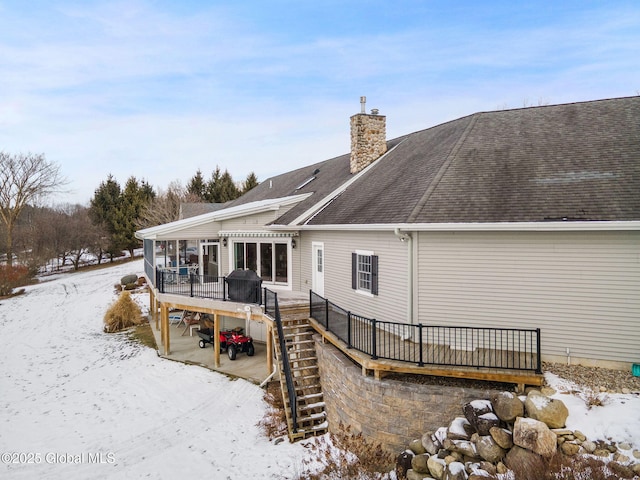 snow covered back of property with a deck