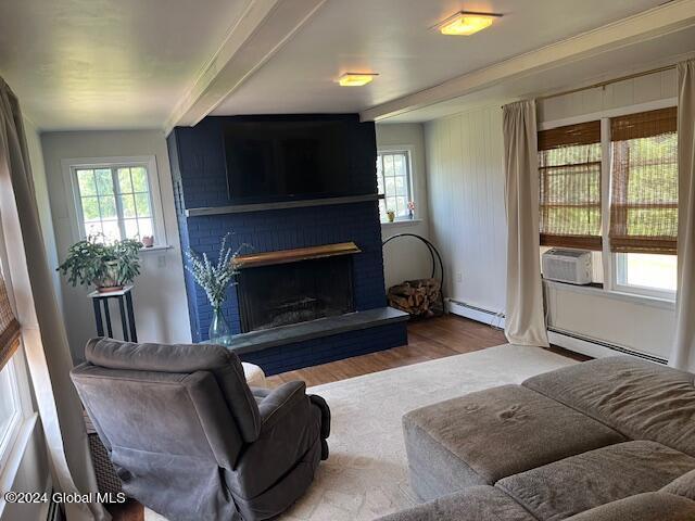 living room with a healthy amount of sunlight, a baseboard heating unit, and a fireplace