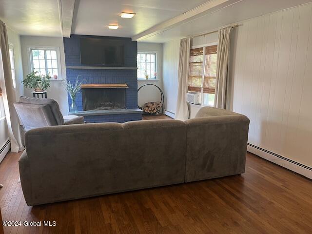 living room with a wealth of natural light, a brick fireplace, and dark hardwood / wood-style floors