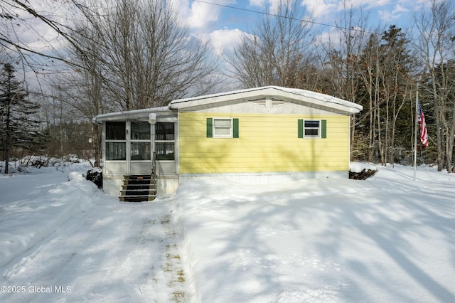 snow covered structure featuring a sunroom