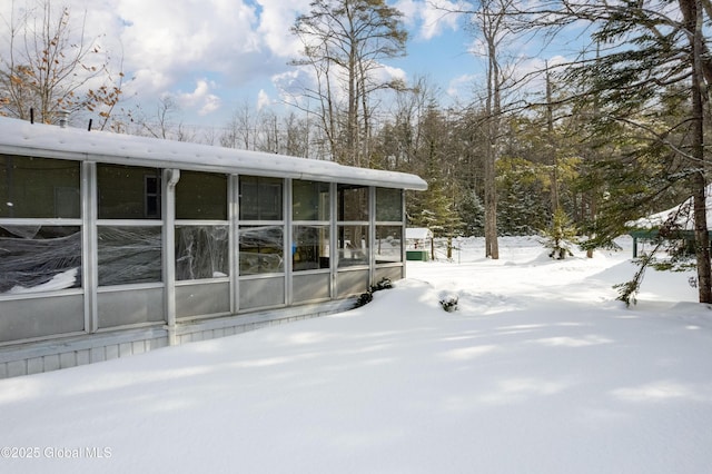 view of snowy exterior featuring a sunroom