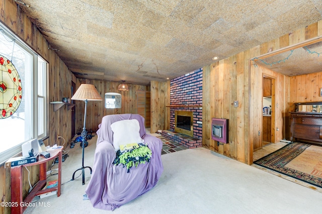 carpeted living room with heating unit, a brick fireplace, and wooden walls