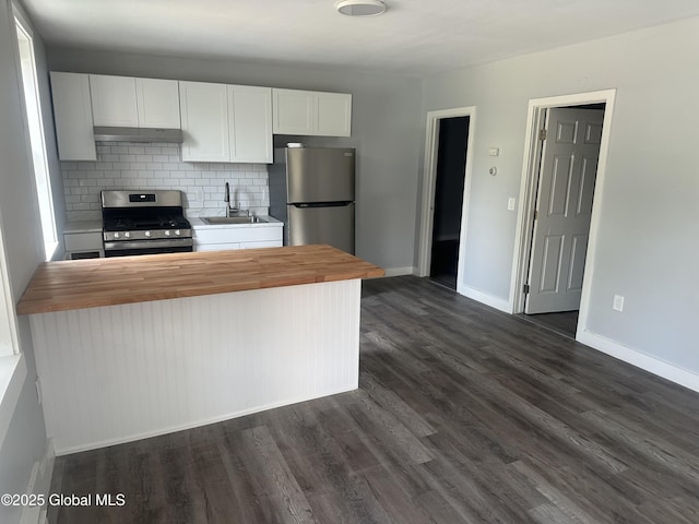 kitchen with wood counters, stainless steel appliances, tasteful backsplash, white cabinets, and sink