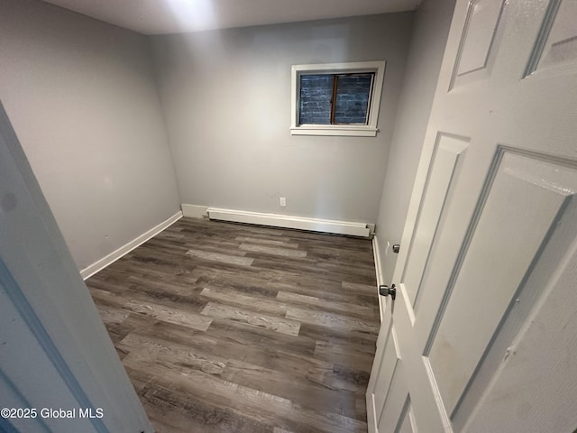 empty room featuring dark wood-type flooring and baseboard heating