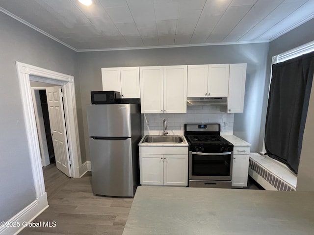 kitchen with radiator, appliances with stainless steel finishes, white cabinets, and sink