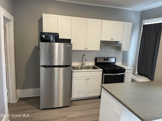 kitchen with white cabinetry, appliances with stainless steel finishes, backsplash, light wood-type flooring, and sink