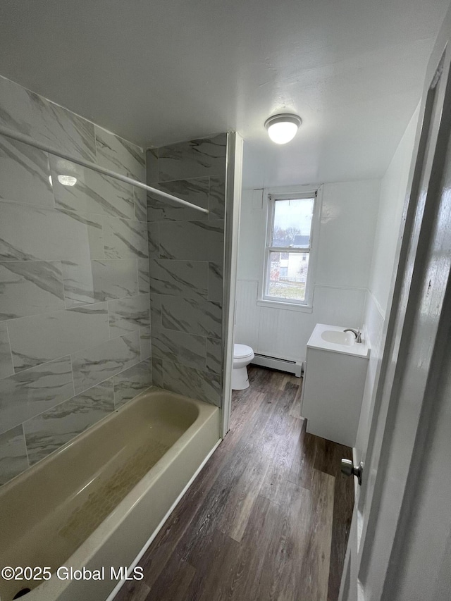 full bathroom with toilet, vanity, tiled shower / bath, wood-type flooring, and baseboard heating