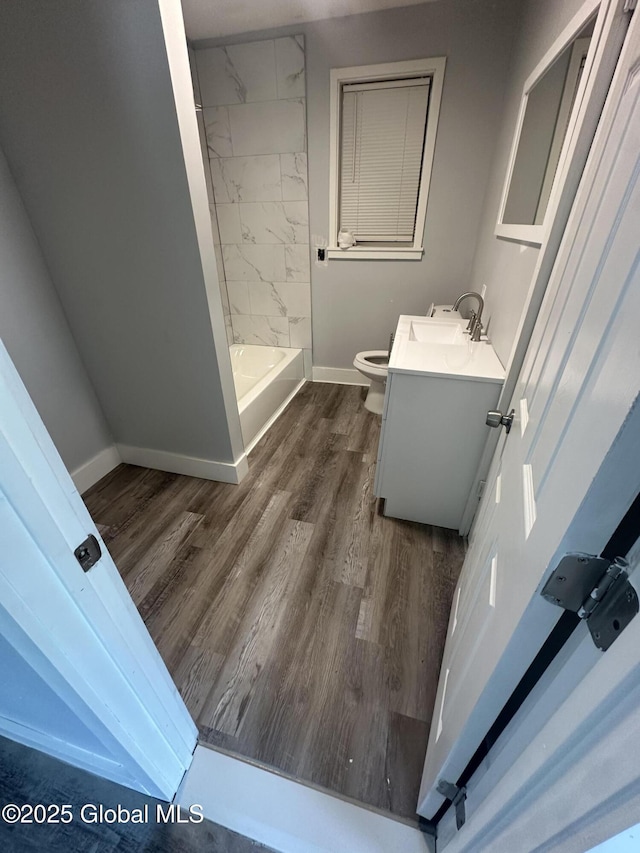 full bathroom with toilet, vanity, tiled shower / bath, and hardwood / wood-style floors