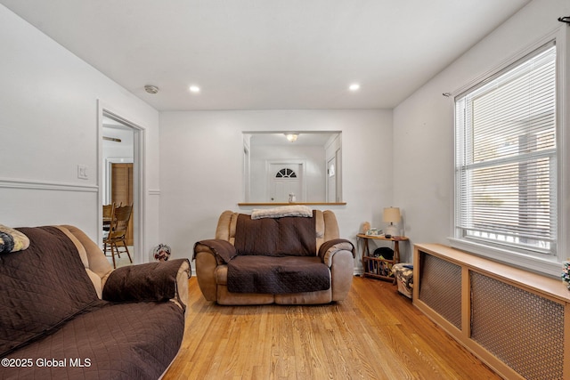 living room featuring a healthy amount of sunlight, radiator heating unit, and light hardwood / wood-style flooring