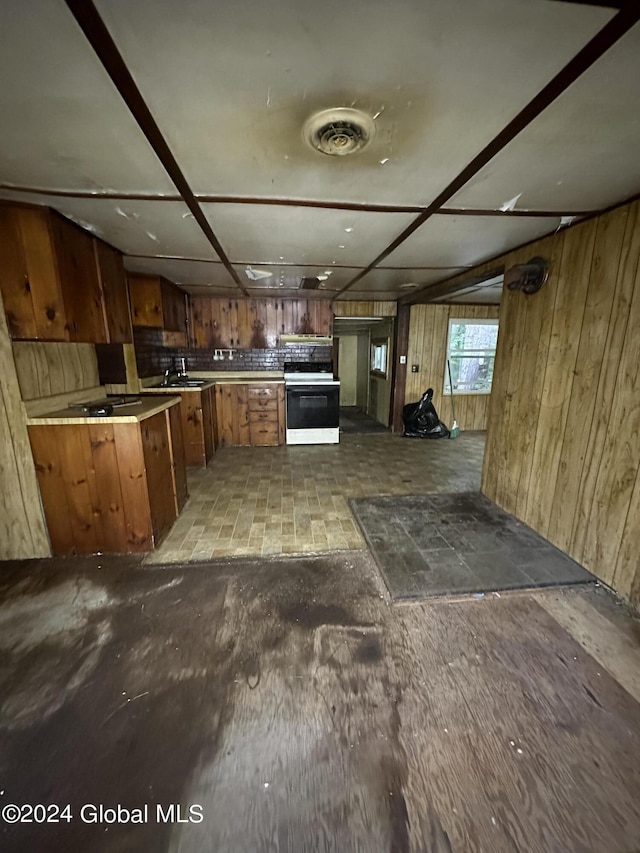 kitchen featuring wood walls, sink, white electric range oven, and kitchen peninsula