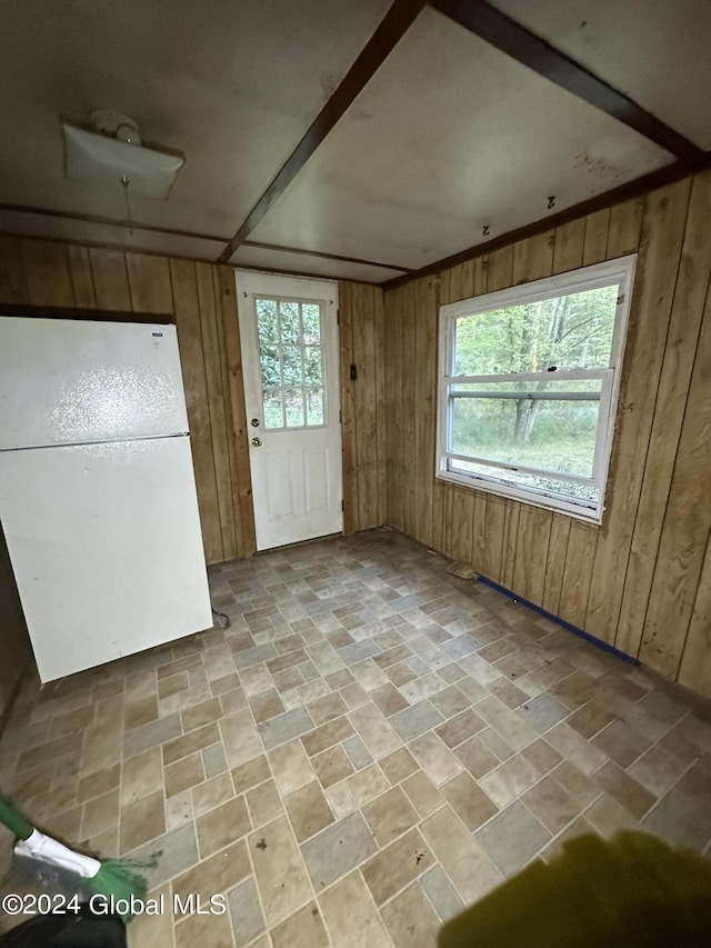 interior space with a wealth of natural light, white fridge, and wooden walls