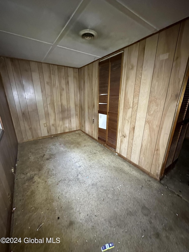 unfurnished bedroom featuring a closet and wood walls