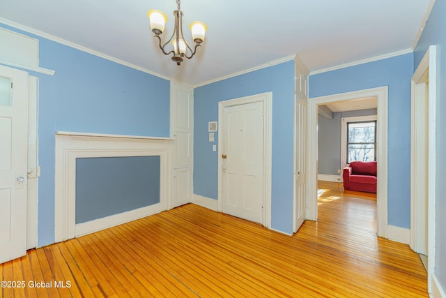 unfurnished living room with an inviting chandelier, light hardwood / wood-style flooring, and ornamental molding