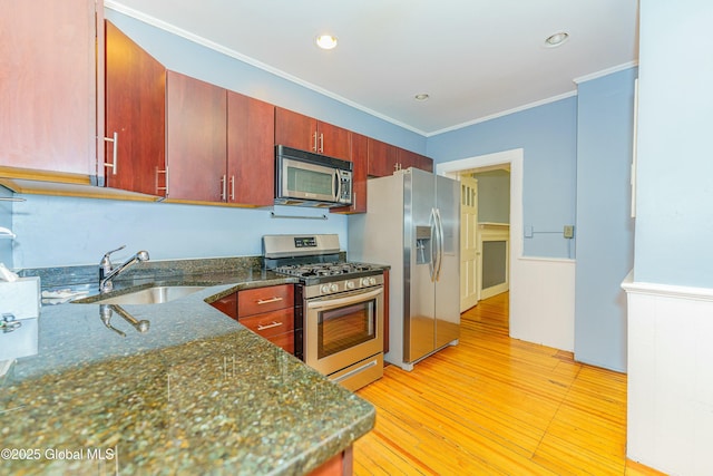 kitchen with appliances with stainless steel finishes, sink, dark stone countertops, light hardwood / wood-style floors, and crown molding