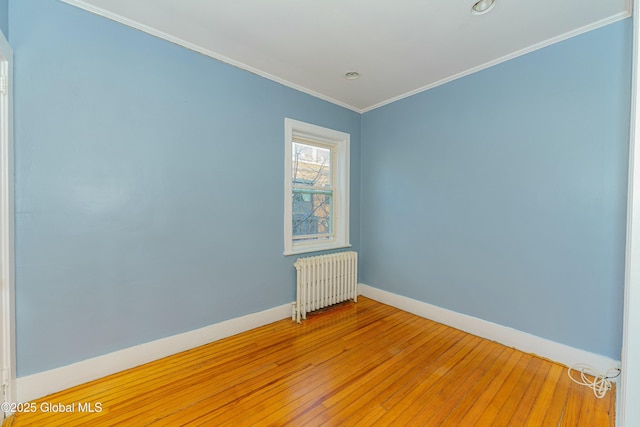 spare room with ornamental molding, wood-type flooring, and radiator heating unit