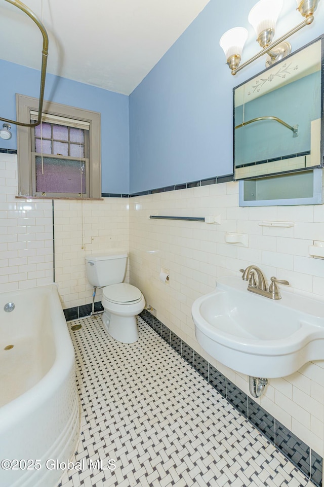 bathroom with toilet, a bath, sink, and tile walls