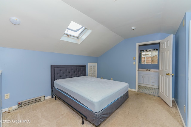 bedroom featuring light colored carpet, vaulted ceiling with skylight, and sink