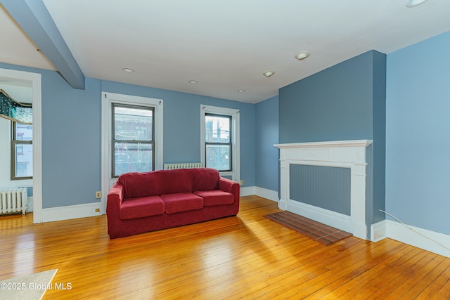 living room featuring a fireplace, radiator heating unit, and light hardwood / wood-style floors