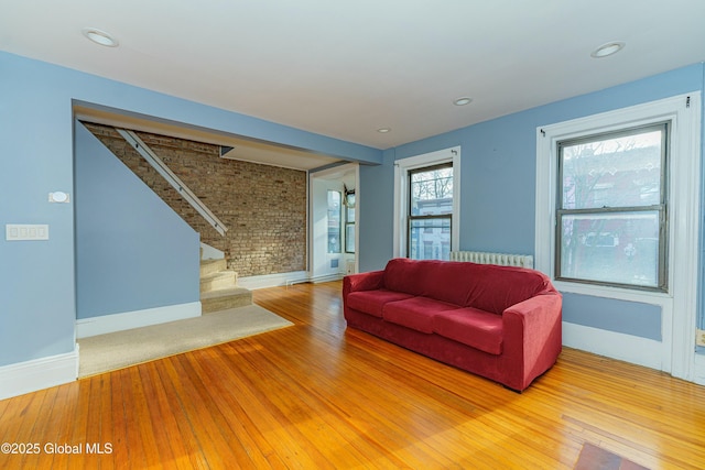 living room featuring hardwood / wood-style floors, radiator, and brick wall