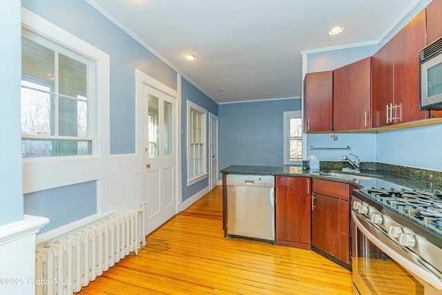 kitchen with sink, crown molding, radiator heating unit, and stainless steel appliances