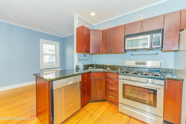 kitchen with light hardwood / wood-style flooring, stainless steel appliances, ornamental molding, kitchen peninsula, and dark stone counters