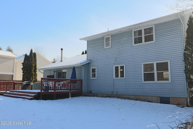 snow covered back of property with a wooden deck