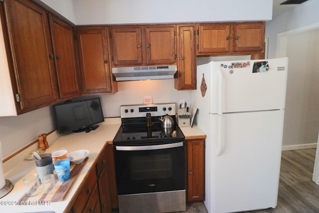 kitchen with wood-type flooring, white fridge, and stainless steel range with electric cooktop