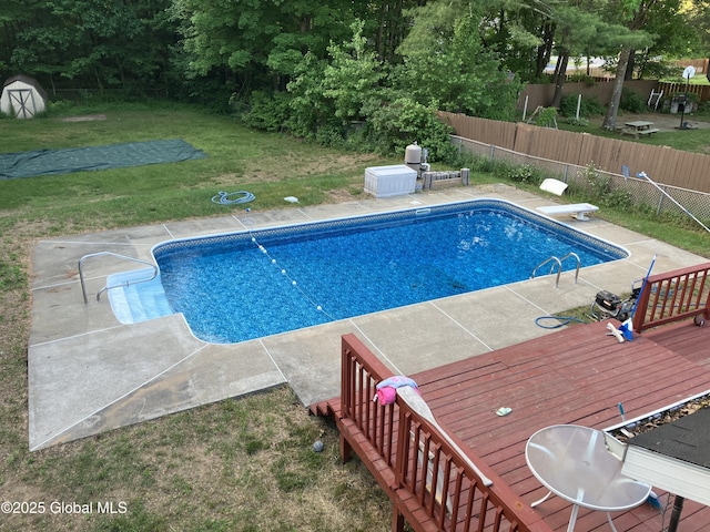 view of pool with a yard, a diving board, and a wooden deck