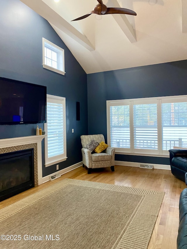 living room featuring a fireplace, wood-type flooring, high vaulted ceiling, and ceiling fan