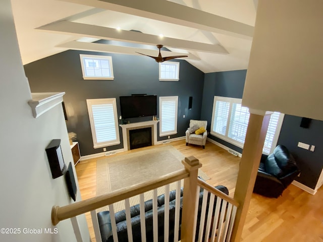 living room featuring ceiling fan, hardwood / wood-style floors, and vaulted ceiling with beams