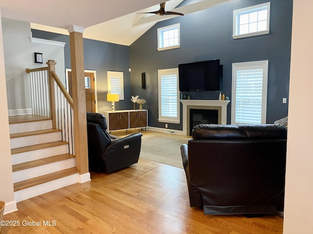 living room featuring decorative columns, light wood-type flooring, a wealth of natural light, and ceiling fan