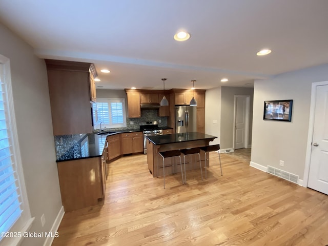 kitchen featuring pendant lighting, sink, decorative backsplash, a center island, and stainless steel appliances