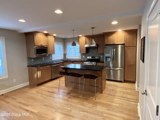 kitchen with sink, hanging light fixtures, light hardwood / wood-style flooring, a kitchen island, and stainless steel appliances