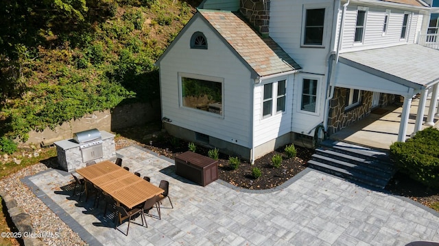 view of side of home with an outdoor kitchen and a patio area