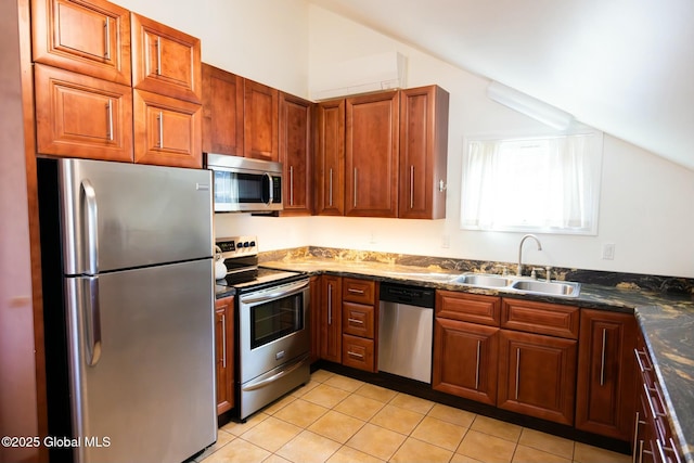 kitchen with lofted ceiling, sink, dark stone countertops, light tile patterned floors, and stainless steel appliances