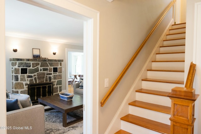 stairway featuring crown molding and a fireplace