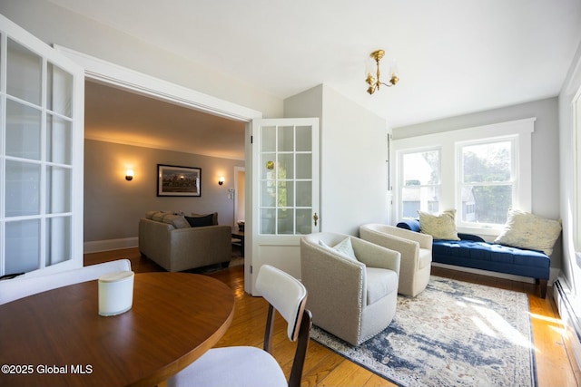 living room featuring hardwood / wood-style flooring, an inviting chandelier, and baseboard heating