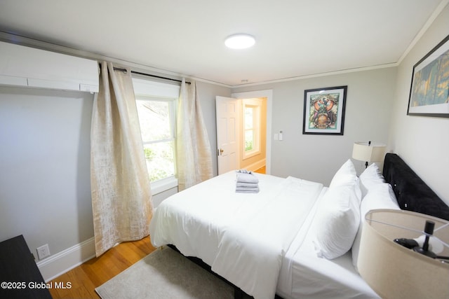 bedroom featuring ornamental molding, a wall mounted air conditioner, and hardwood / wood-style floors