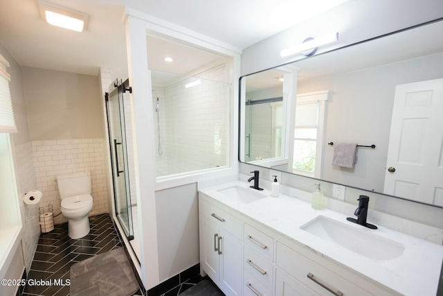 bathroom featuring tile patterned floors, toilet, tile walls, vanity, and a shower with door