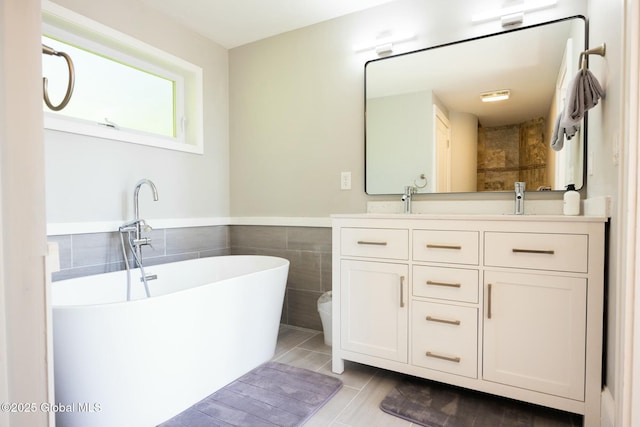 bathroom with vanity, tile walls, and a tub