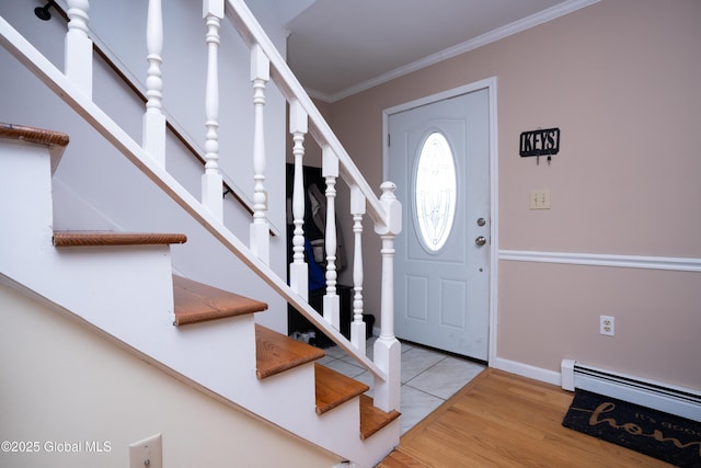 foyer entrance with a baseboard heating unit, ornamental molding, and light hardwood / wood-style floors