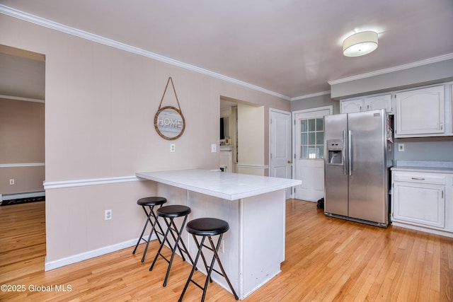 kitchen with stainless steel fridge with ice dispenser, white cabinetry, a breakfast bar area, kitchen peninsula, and crown molding