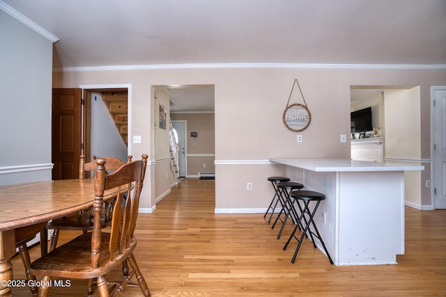 kitchen featuring light hardwood / wood-style flooring, a breakfast bar area, ornamental molding, and kitchen peninsula