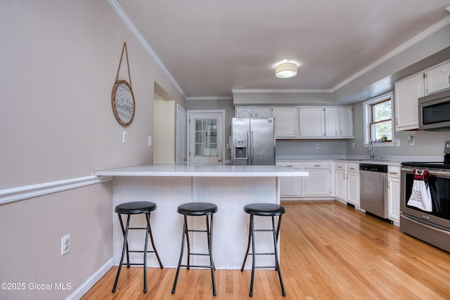 kitchen featuring white cabinetry, stainless steel appliances, a kitchen breakfast bar, and kitchen peninsula