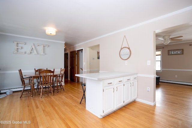 kitchen featuring a breakfast bar, crown molding, a baseboard radiator, light hardwood / wood-style floors, and white cabinets