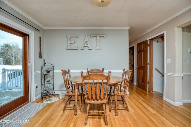 dining room with ornamental molding, a baseboard heating unit, and light wood-type flooring