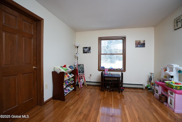 rec room with a baseboard heating unit and hardwood / wood-style floors