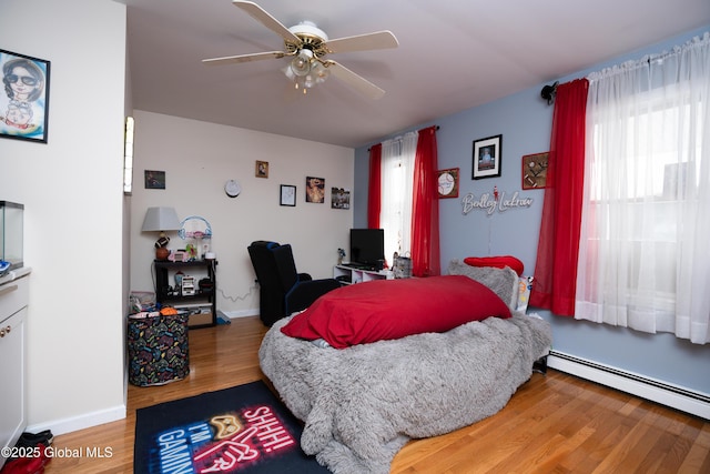 bedroom with a baseboard heating unit, hardwood / wood-style floors, and ceiling fan