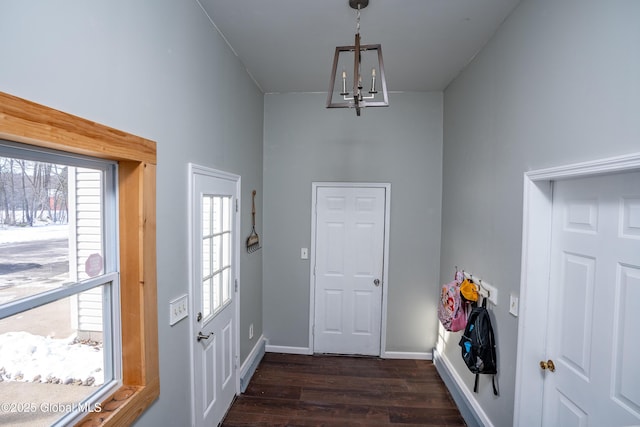 entryway with an inviting chandelier and dark wood-type flooring